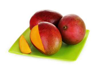 Ripe appetizing mango on green plate isolated on white