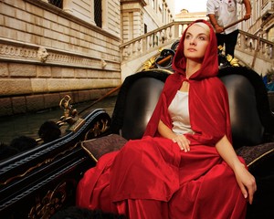 Beautiful woman in red cloak riding on gondola