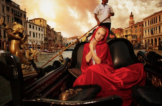 Beautiful woman in red cloak riding on gondola