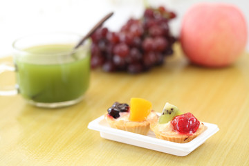 Fruit tart with green tea on wood background