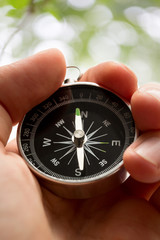 Hand holding silver black compass
