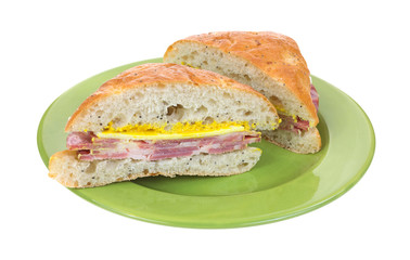 Cut capicolla sandwich on green plate