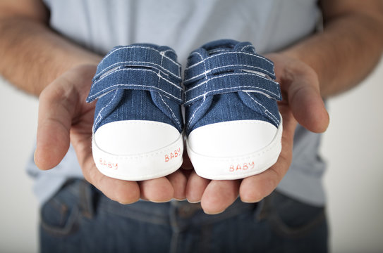 Man Holding Baby Shoes