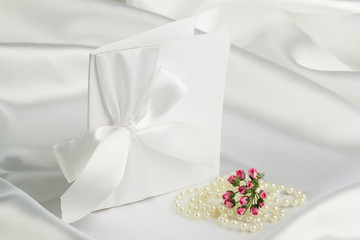Fototapeta na wymiar handmade wedding card on a white satin fabric