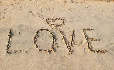 Word LOVE on wet sand