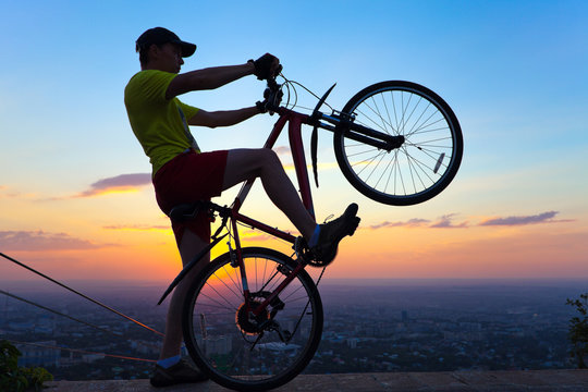 young man with a bicycle at sunset.