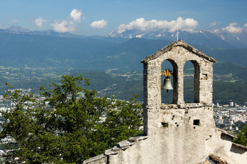 Church tower with bell. View on the alps