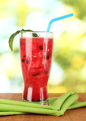 A glass of fresh watermelon juice on green background close-up