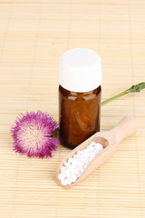 medicine bottle with tablets and flower on bamboo mat