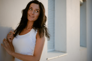 Young beautiful happy woman standing at white wall and looking b