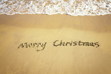 Merry Christmas handwritten in sand on beach