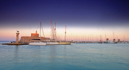 Rhodes harbor and windmills in Greece at sunset