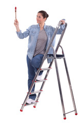 young female painter on ladder with raised brush