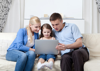 Happy family sit on the couch with laptop having a rest