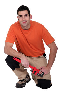 Kneeling handyman holding a pipe wrench