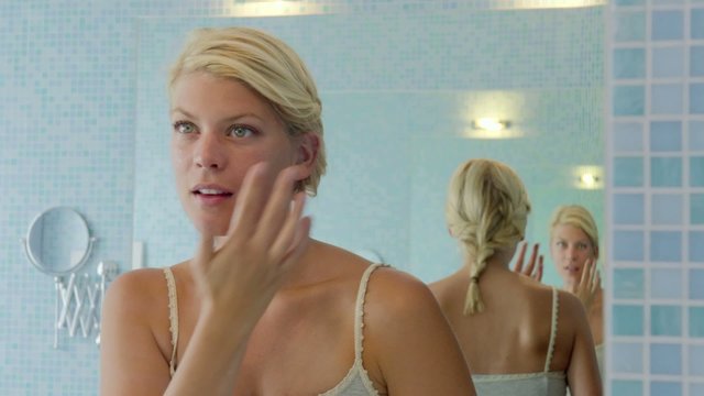 Female beauty, young woman applying lotion on face at home