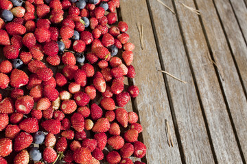 wild strawberry and bilberry  are on the wooden table