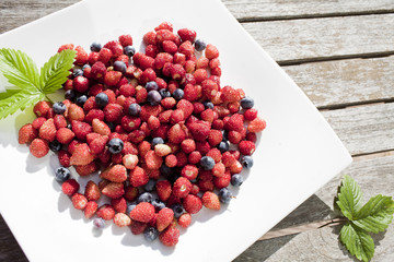 wild strawberry and bilberry  are on the white plate