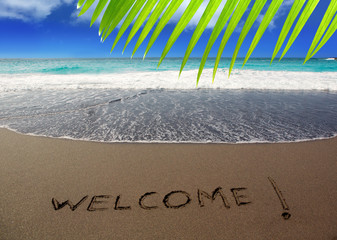 Brown sand beach with written word Welcome