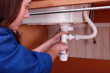 Woman fixing the plumbing on a sink