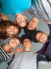 Six happy teenagers standing in the circle and looking down