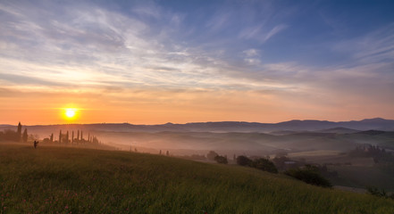 Val d'Orcia after sunrise with photographer, Tuscany, Italy