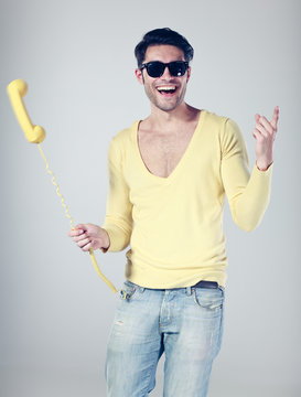 Attractive Man Smiling And Playing With  A Yellow Phone