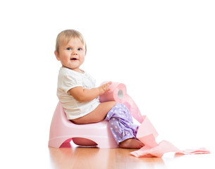 smiling baby sitting on chamber pot with toilet paper roll