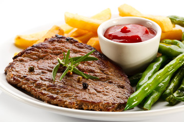 Grilled steaks, French fries and vegetables