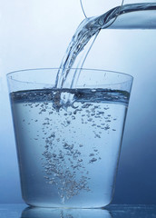 Pouring a mineral water into a glass   on blue background