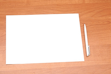Blank sheet of paper with pen on wooden background