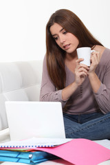 Young woman checking her emails while drinking a cup of tea