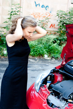 Beautiful young woman near the broken car