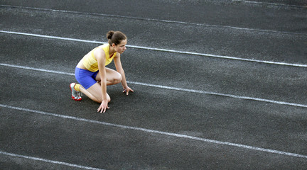Fototapeta premium Athletic teenage girl in start position on track .