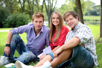 Happy group of students with a notebook smiling outdoors