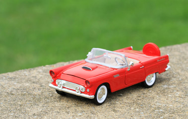 Retro toy car on road and green grass background