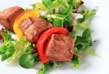 Grilled pork skewer with salad greens