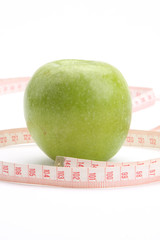 A green apple and a measuring tape