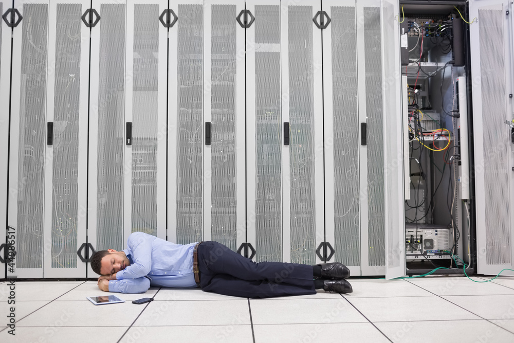 Poster man sleeping in front of servers