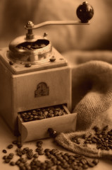 Alte Hand Kaffeemühle mit Kaffeebohnen und Jutesäcken dekoriert im weichen Licht für...