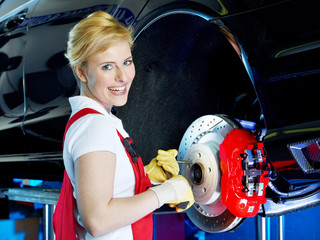 Female apprentice in a garage learning to fix a brake
