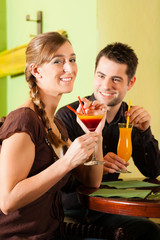 Young couple drinking cocktails in bar or restaurant