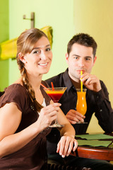 Young couple drinking cocktails in bar or restaurant