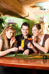 Young people drinking cocktails in bar or restaurant
