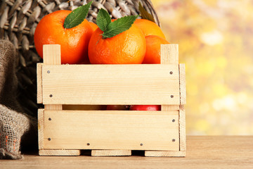 Ripe tasty tangerines with leaves in wooden box