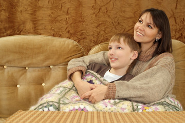 A nice Caucasian mother with her son sitting on the couch