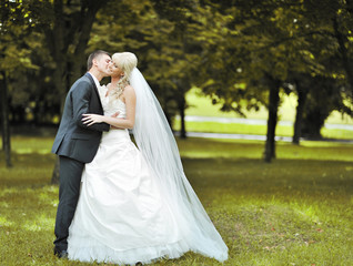 Kissing wedding couple in a park