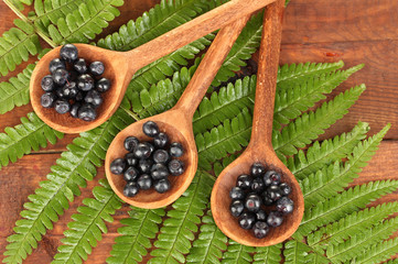 Tasty blueberries in wooden spoons on wooden background