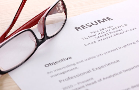 Closeup of resume with glasses on wooden table