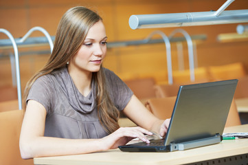 young student girl working with laptop in library